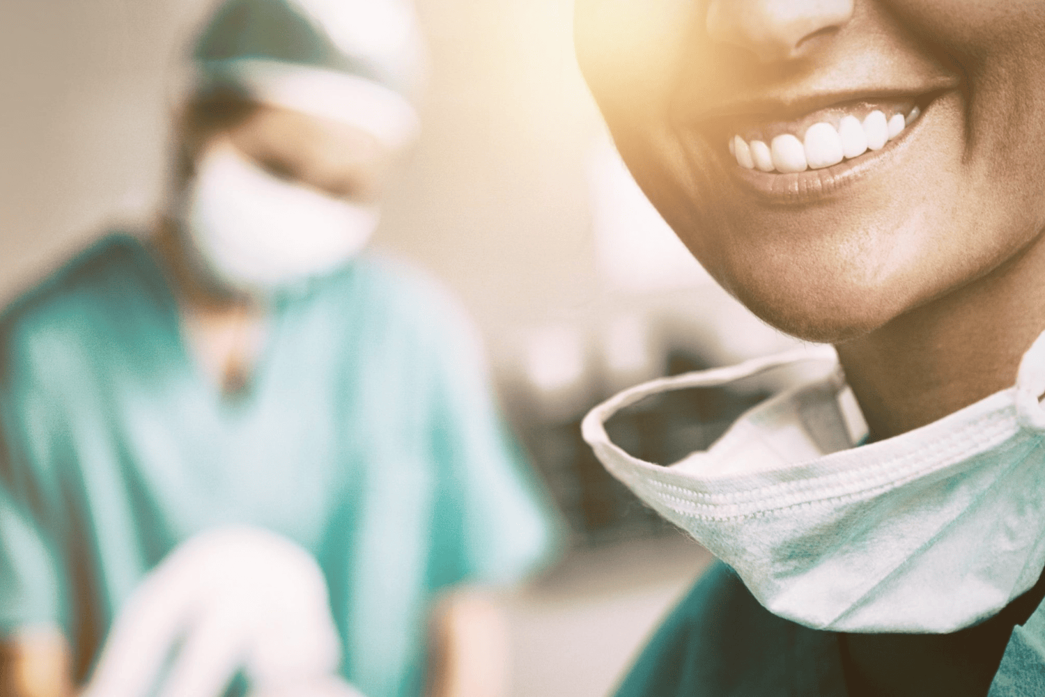 Physicians_compressed Physician in scrubs smiling with another physician in the background
